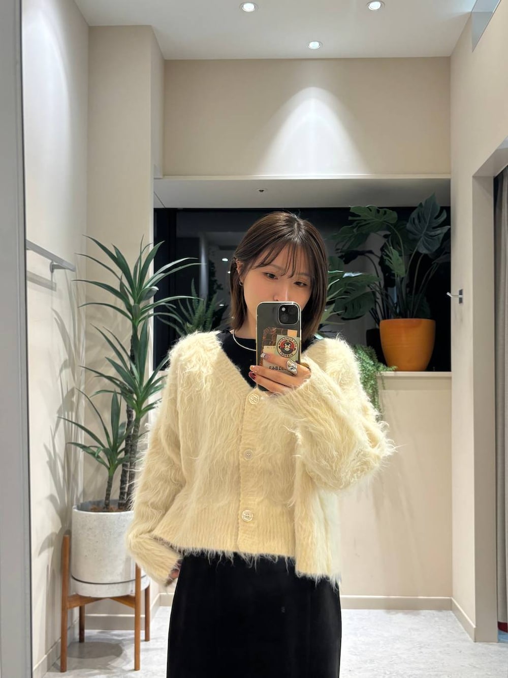 ブラック系のブーツ、ブラック系のスカート、ホワイト系のカーディガン/ボレロを着用したレディースの冬コーディネートの3枚目の写真