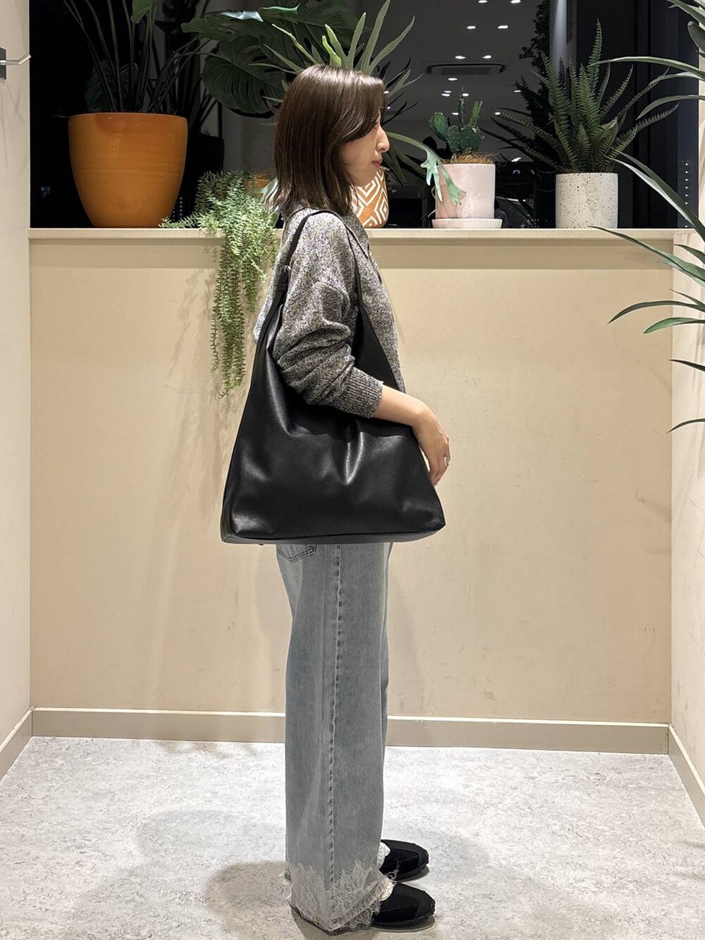 ブラック系のショルダーバッグ、ブルー系のデニムパンツ、ブラック系のスニーカーを着用したレディースの春コーディネートの3枚目の写真