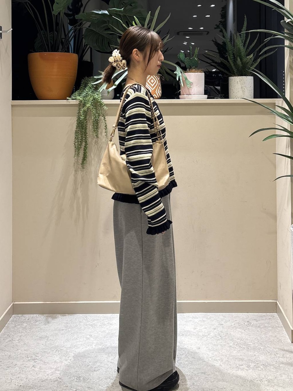 ブラック系のブーツ、ベージュ系のショルダーバッグ、グレー系のスウェットパンツを着用したレディースの冬コーディネートの4枚目の写真