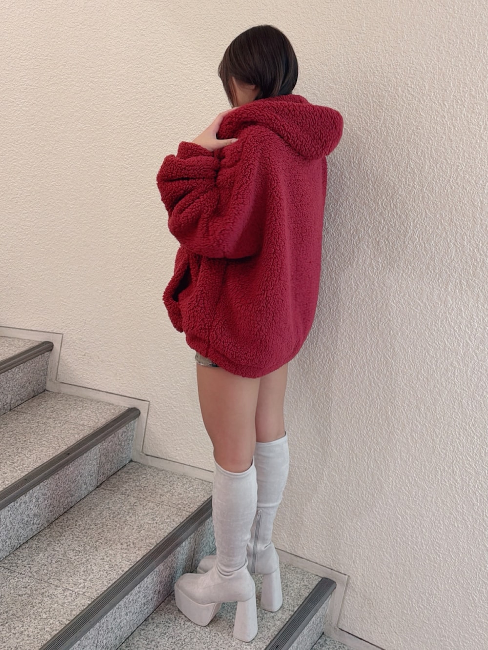 レッド系のパーカー、ホワイト系のブーツ、その他のデニムスカートを着用したレディースの秋コーディネートの2枚目の写真