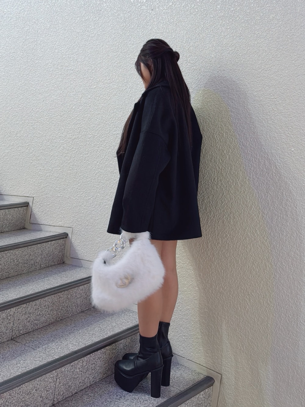 ホワイト系のニット/セーター、ブラック系のチェスターコート、ブラック系のデニムスカートを着用したレディースの秋コーディネートの2枚目の写真