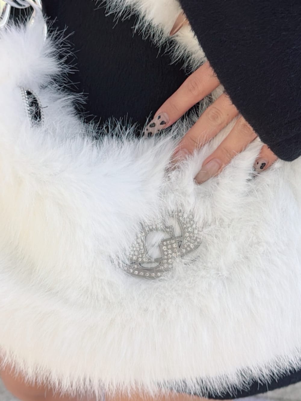 ホワイト系のニット/セーター、ブラック系のチェスターコート、ブラック系のデニムスカートを着用したレディースの秋コーディネートの4枚目の写真