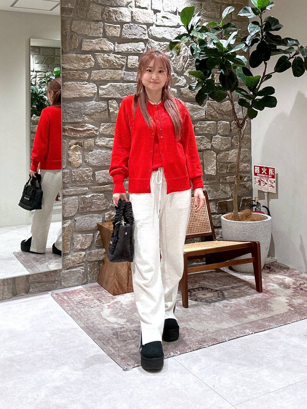 ホワイト系のスウェットパンツ、ブラック系のトートバッグ、レッド系のニット/セーターを着用したレディースの冬コーディネートの2枚目の写真