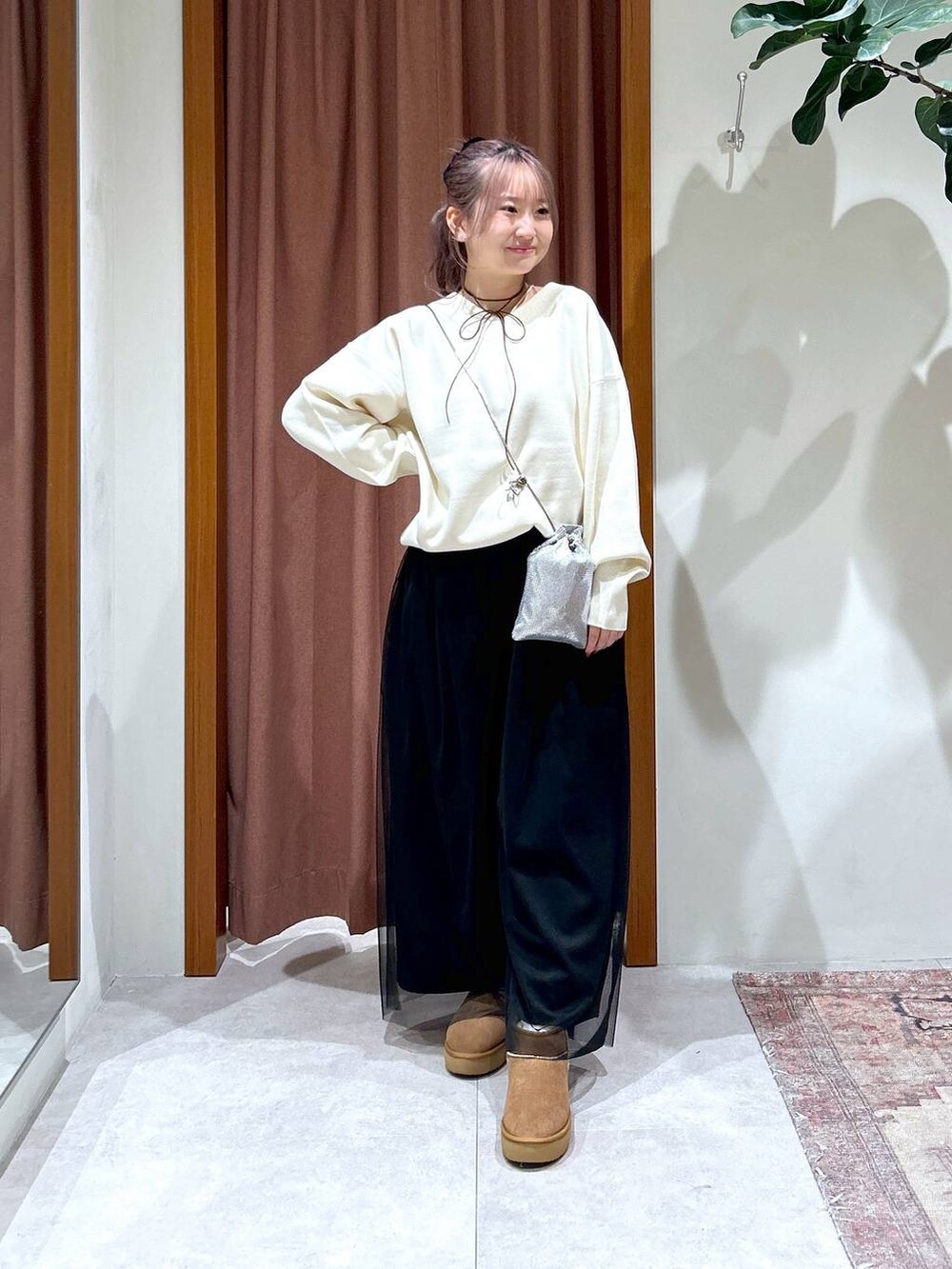 レッド系のニット/セーター、ベージュ系のブーツ、シルバー系のショルダーバッグを着用したレディースの秋コーディネートの2枚目の写真