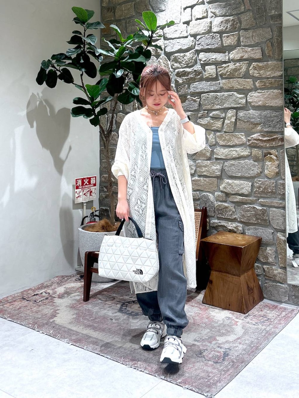 ホワイト系のトートバッグ、ブルー系のキャミソール、ホワイト系のスニーカーを着用したレディースの春コーディネートの2枚目の写真