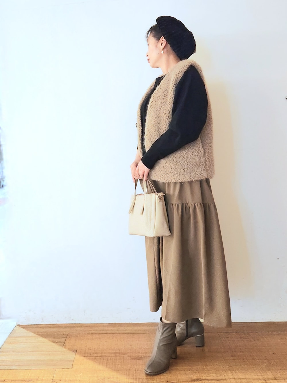 ベージュ系のトートバッグ、ブラウン系のブーツ、ブラック系のワンピースを着用したレディースの秋コーディネートの2枚目の写真