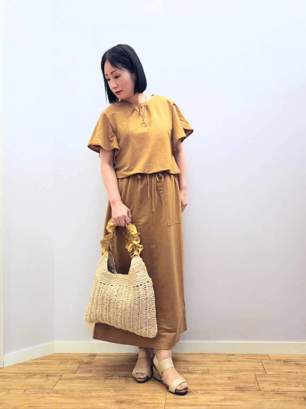 ゴールド系のサンダル、イエロー系のトートバッグ、イエロー系のスカートを着用したレディースの夏コーディネートの2枚目の写真