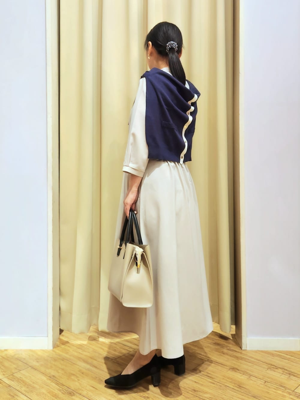 ブラック系のパンプス、ベージュ系のトートバッグ、ベージュ系のワンピースを着用したレディースの春コーディネートの3枚目の写真