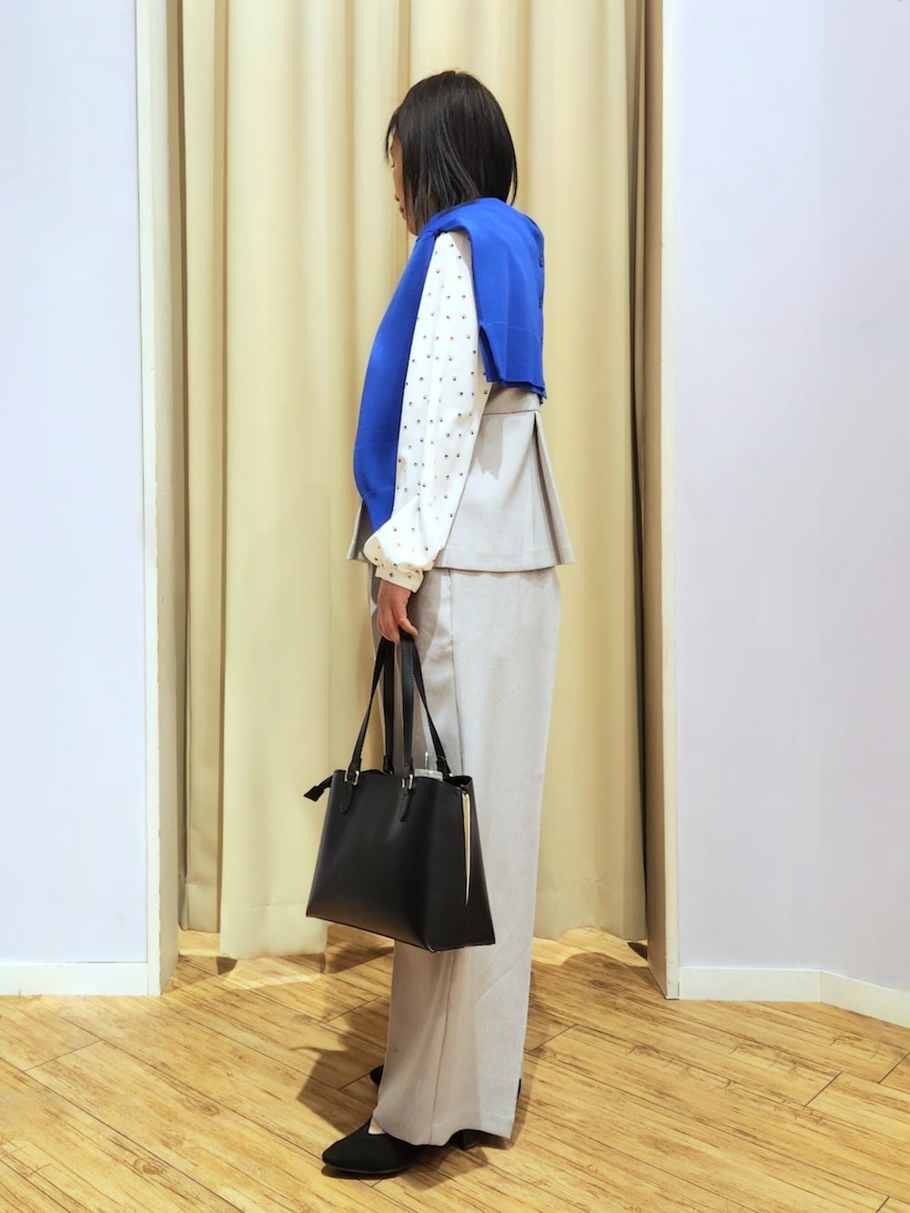 ブラック系のトートバッグ、ブラック系のパンプス、グレー系のパンツドレスを着用したレディースの春コーディネートの2枚目の写真