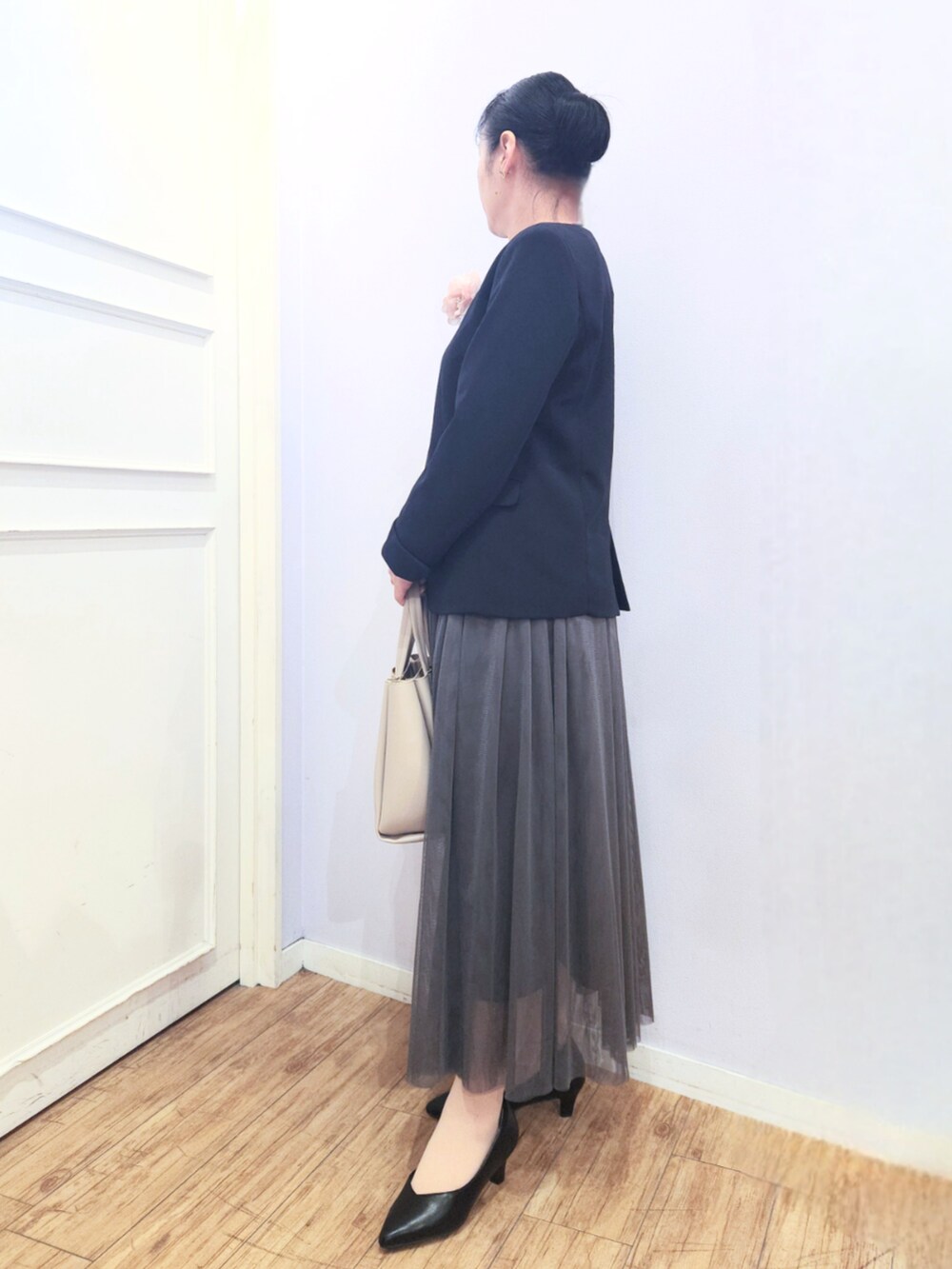 グレー系のトートバッグ、ブラック系のパンプス、グレー系のスカートを着用したレディースの冬コーディネートの2枚目の写真