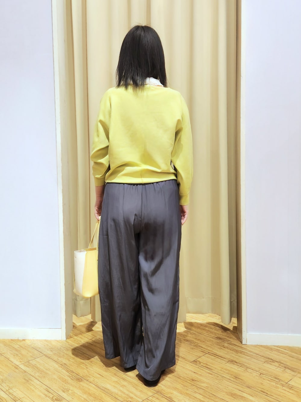 イエロー系のトートバッグ、ブラック系のパンプス、グレー系のその他パンツを着用したレディースの春コーディネートの3枚目の写真