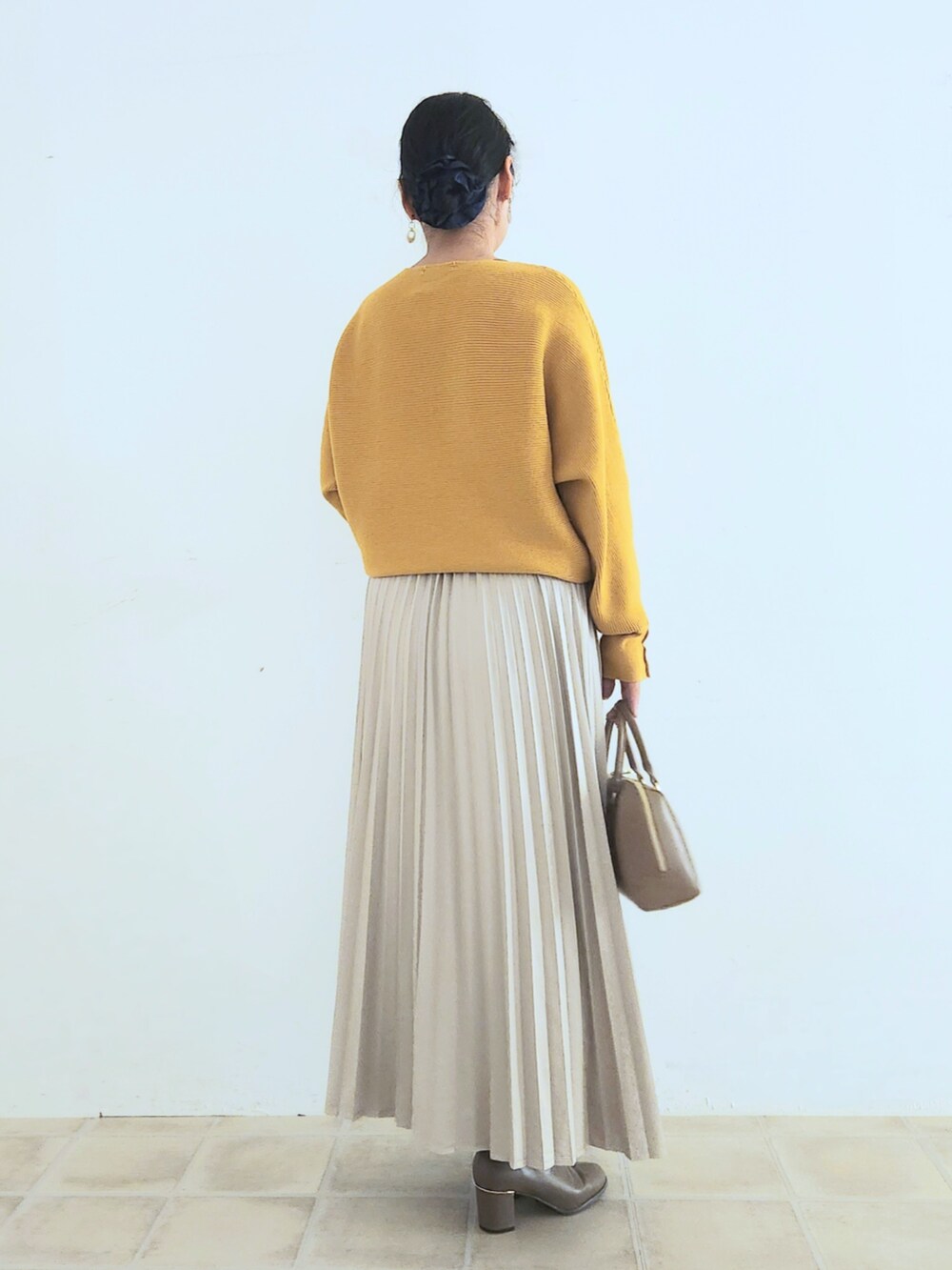 ベージュ系のスカート、ブラウン系のブーツ、イエロー系のニット/セーターを着用したレディースの秋コーディネートの4枚目の写真