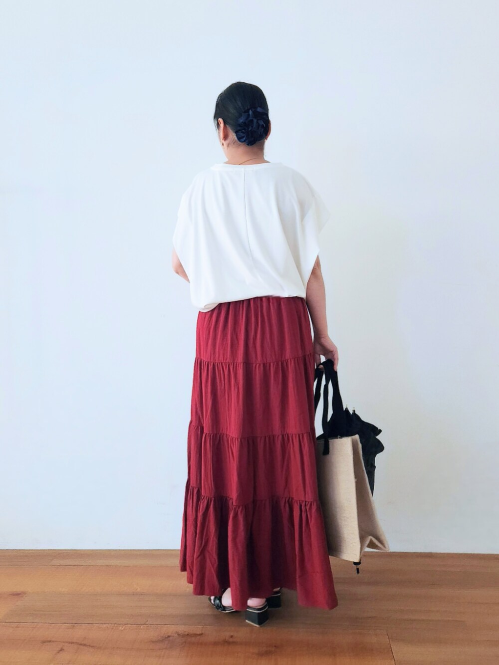 ブラック系のトートバッグ、レッド系のスカート、ホワイト系のTシャツ/カットソーを着用したレディースの夏コーディネートの5枚目の写真