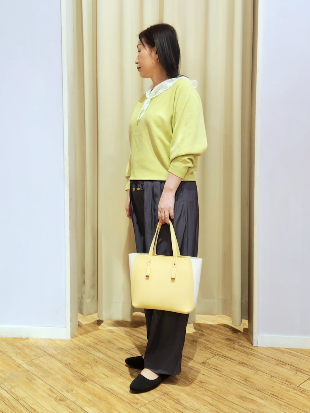 イエロー系のトートバッグ、ブラック系のパンプス、グレー系のその他パンツを着用したレディースの春コーディネートの2枚目の写真
