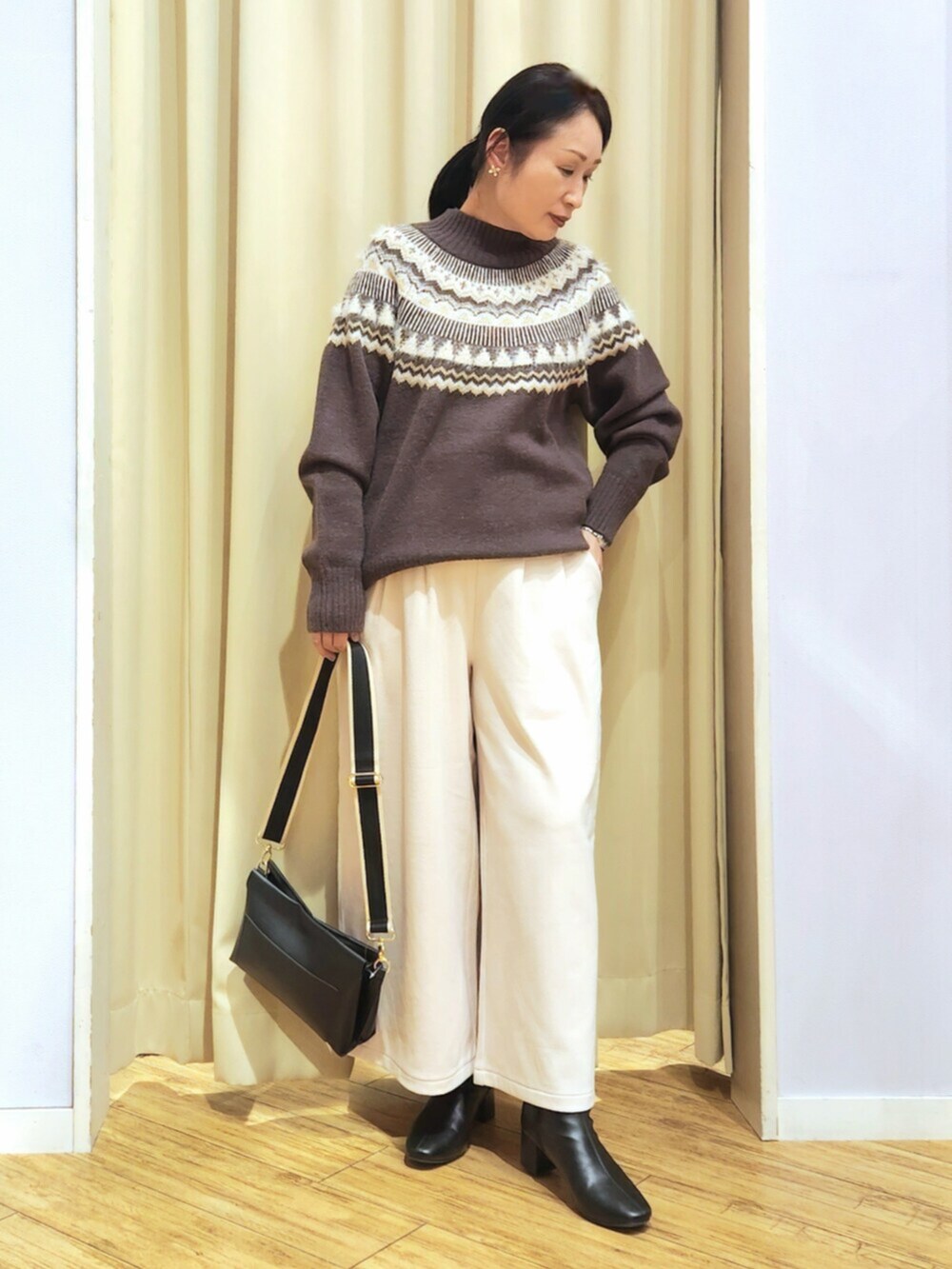 ホワイト系のその他パンツ、ブラウン系のニット/セーター、ブラック系のショルダーバッグを着用したレディースの冬コーディネートの2枚目の写真