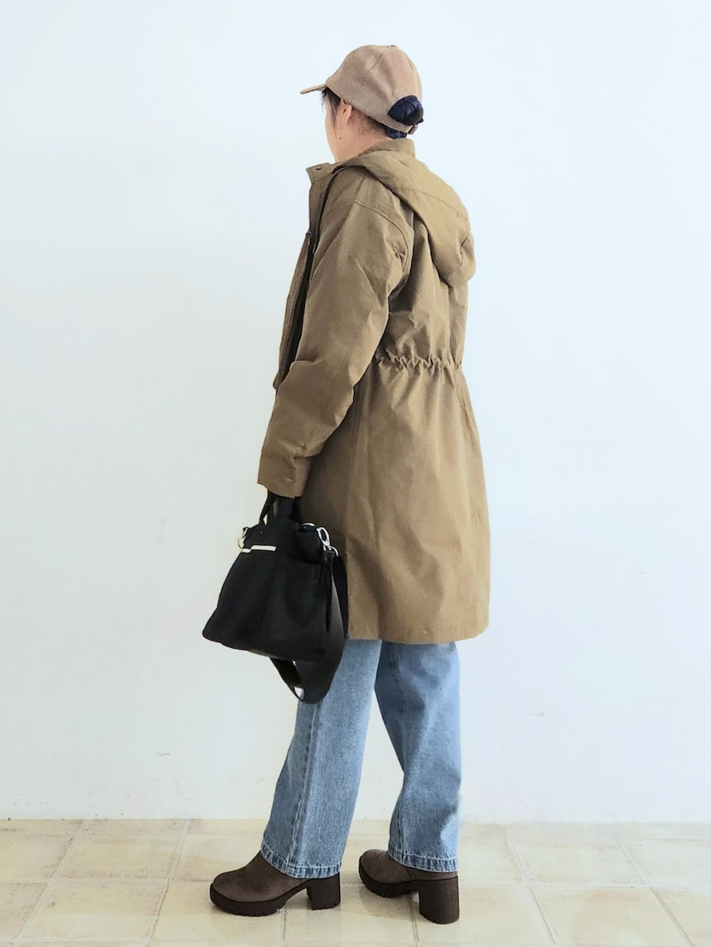 ブルー系のデニムパンツ、ブラウン系のブーツ、ブラック系のトートバッグを着用したレディースの秋コーディネートの2枚目の写真