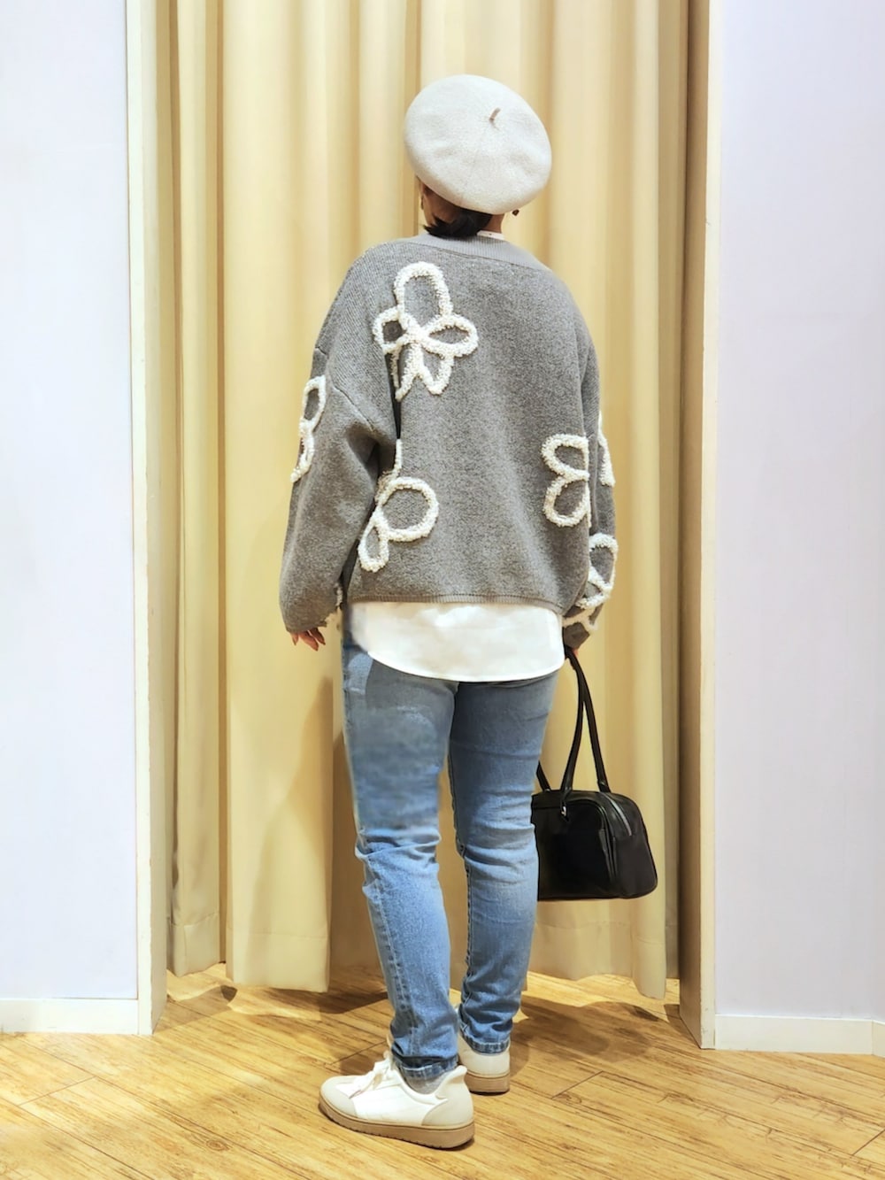 ホワイト系のスニーカー、ブラック系のボストンバッグ、ブルー系のデニムパンツを着用したレディースの冬コーディネートの4枚目の写真