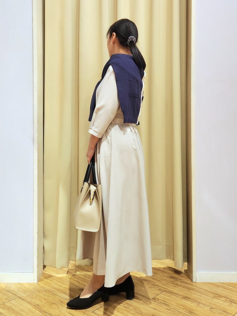 ブラック系のパンプス、ベージュ系のトートバッグ、ベージュ系のワンピースを着用したレディースの春コーディネートの2枚目の写真