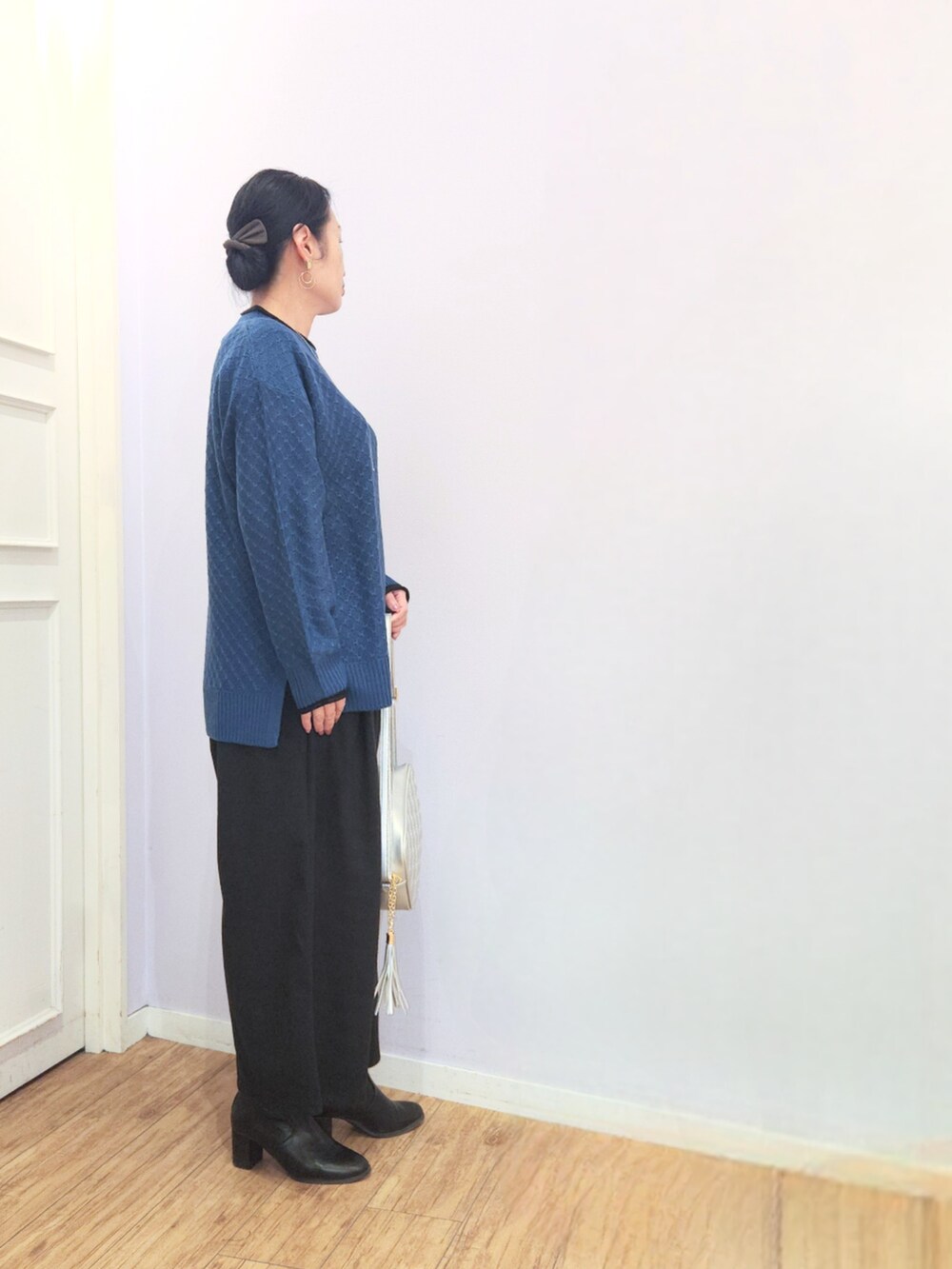 ブラック系のブーツ、ブルー系のニット/セーター、シルバー系のショルダーバッグを着用したレディースの冬コーディネートの2枚目の写真