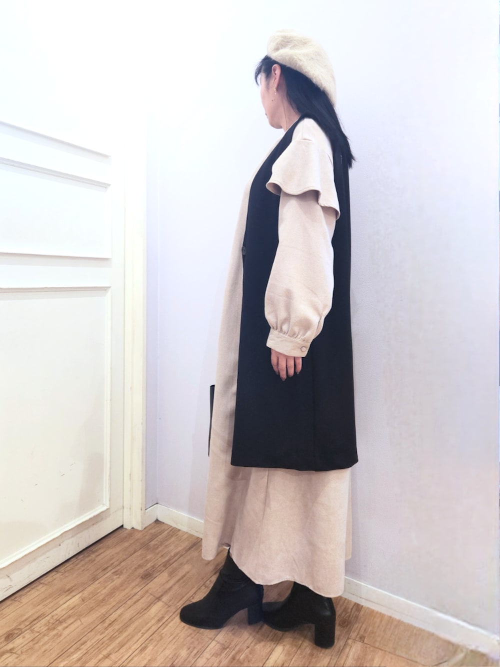 ブラック系のブーツ、ベージュ系のワンピース、ブラック系のベストを着用したレディースの冬コーディネートの2枚目の写真