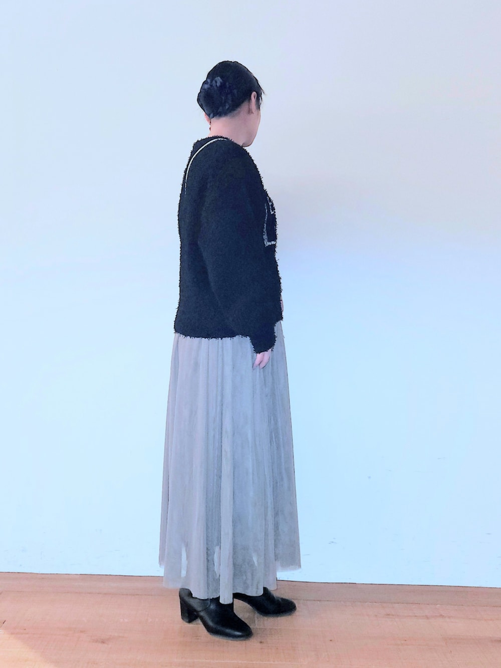 ブラック系のブーツ、シルバー系のショルダーバッグ、ブラウン系のスカートを着用したレディースの冬コーディネートの2枚目の写真