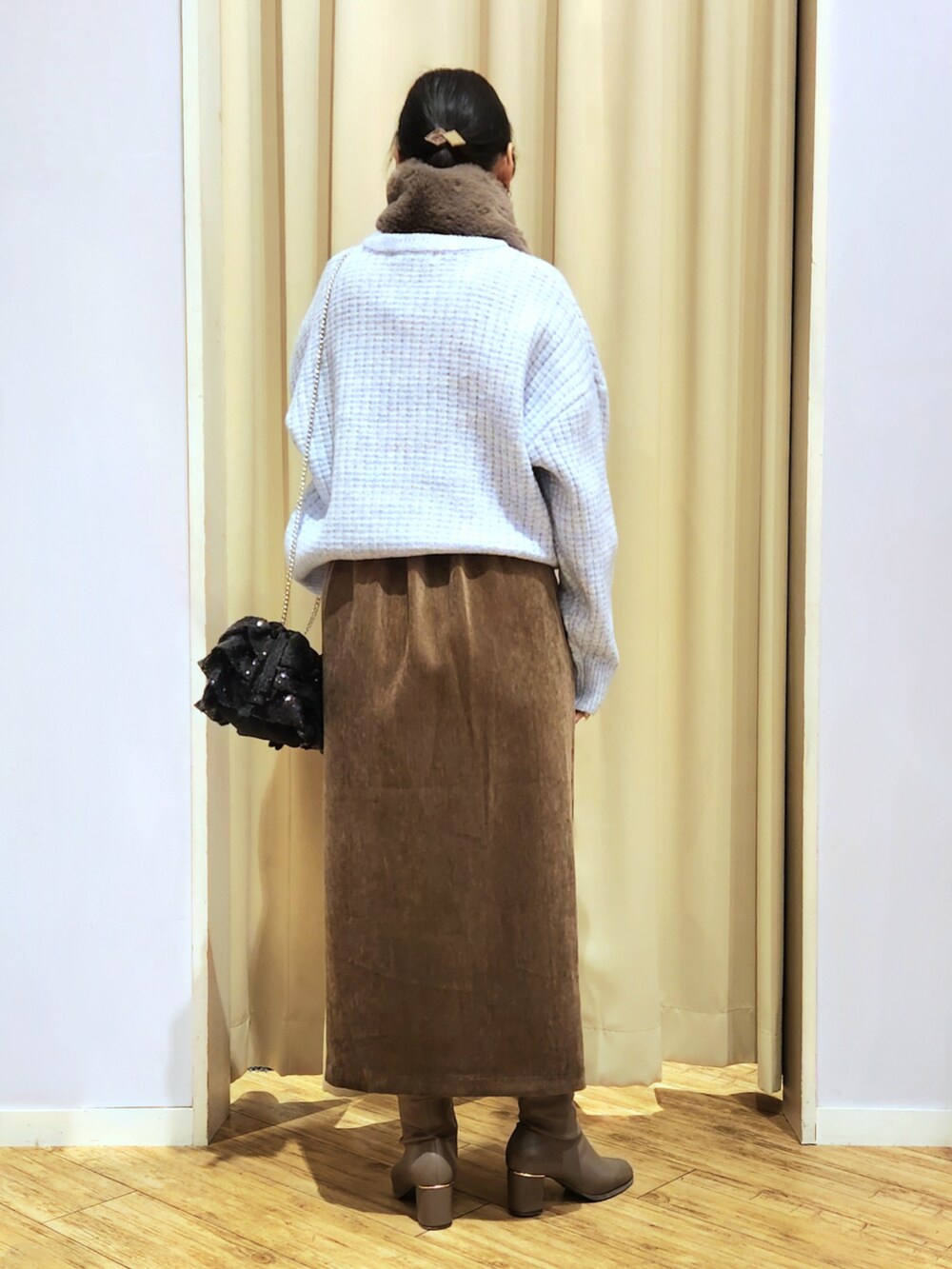 ブラウン系のブーツ、ブラウン系のスカート、ブラック系のショルダーバッグを着用したレディースの冬コーディネートの3枚目の写真