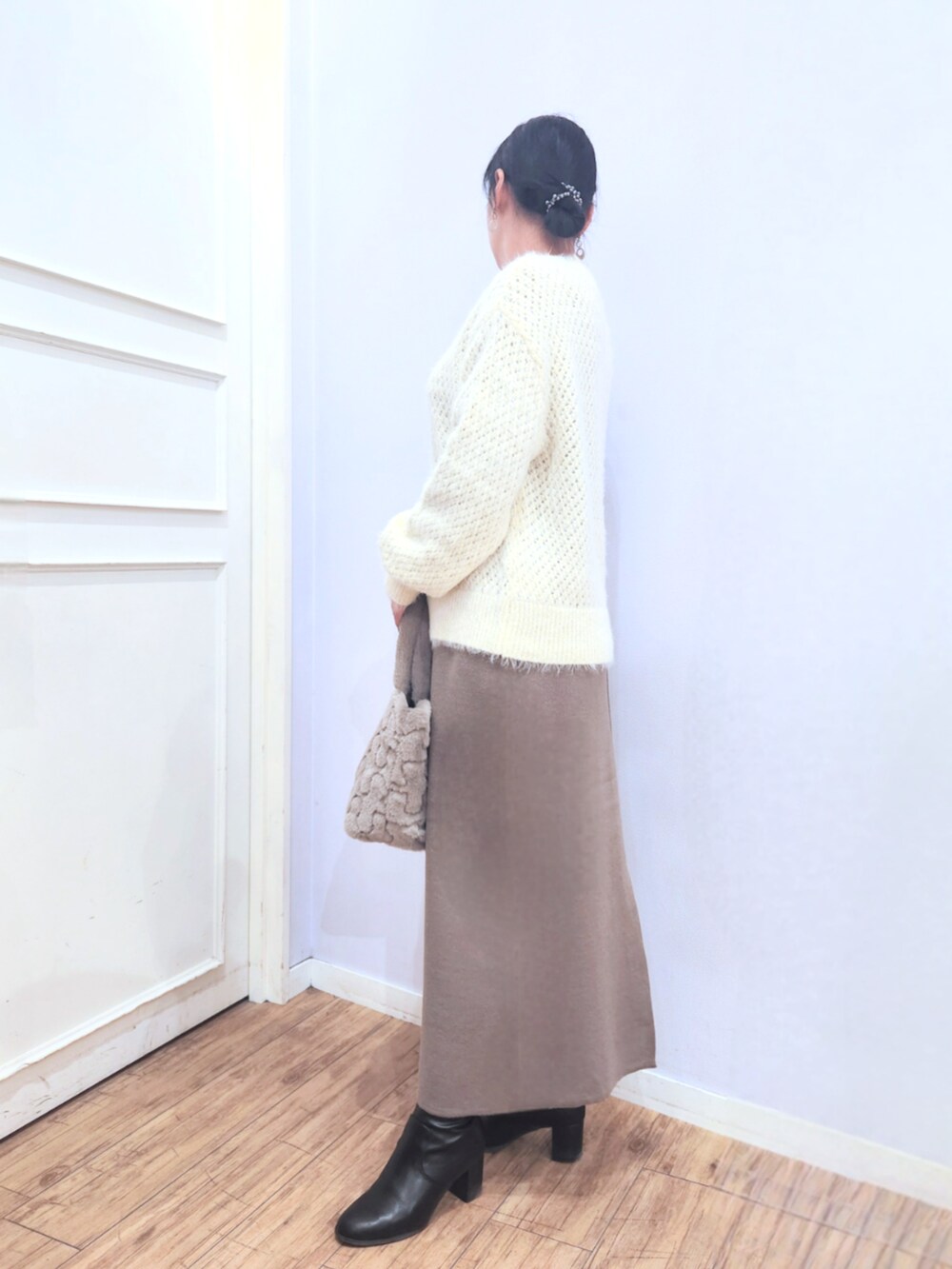ホワイト系のニット/セーター、ブラック系のブーツ、ベージュ系のトートバッグを着用したレディースの冬コーディネートの2枚目の写真