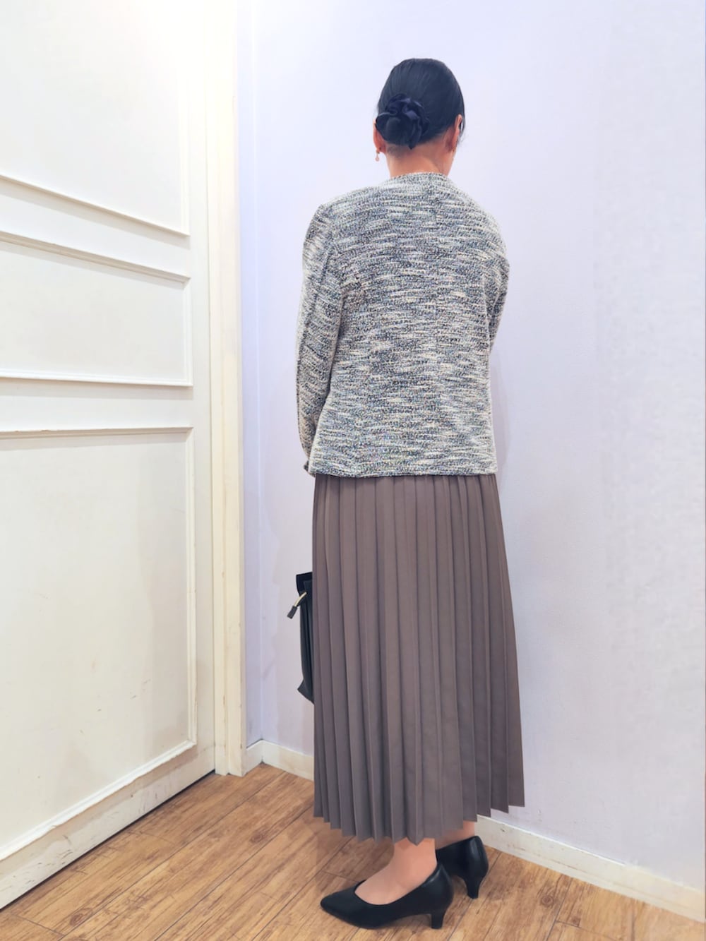 ブラウン系のスカート、ブラック系のパンプス、ブラック系のノーカラージャケットを着用したレディースの冬コーディネートの3枚目の写真