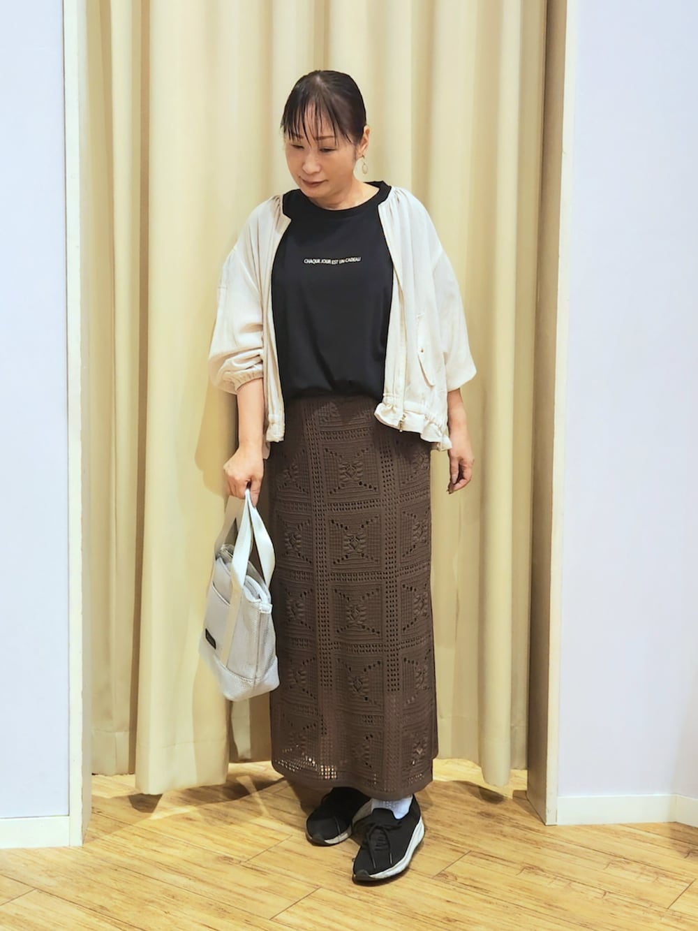 ブラック系のスニーカー、ブラウン系のスカート、ブラック系のTシャツ/カットソーを着用したレディースの夏コーディネートの2枚目の写真