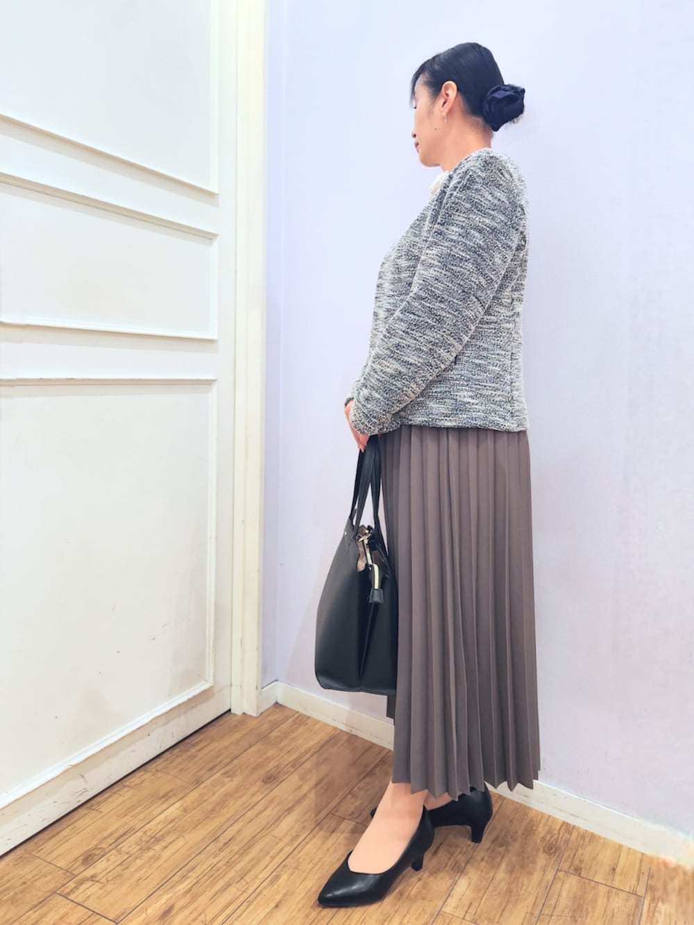 ブラウン系のスカート、ブラック系のパンプス、ブラック系のノーカラージャケットを着用したレディースの冬コーディネートの2枚目の写真