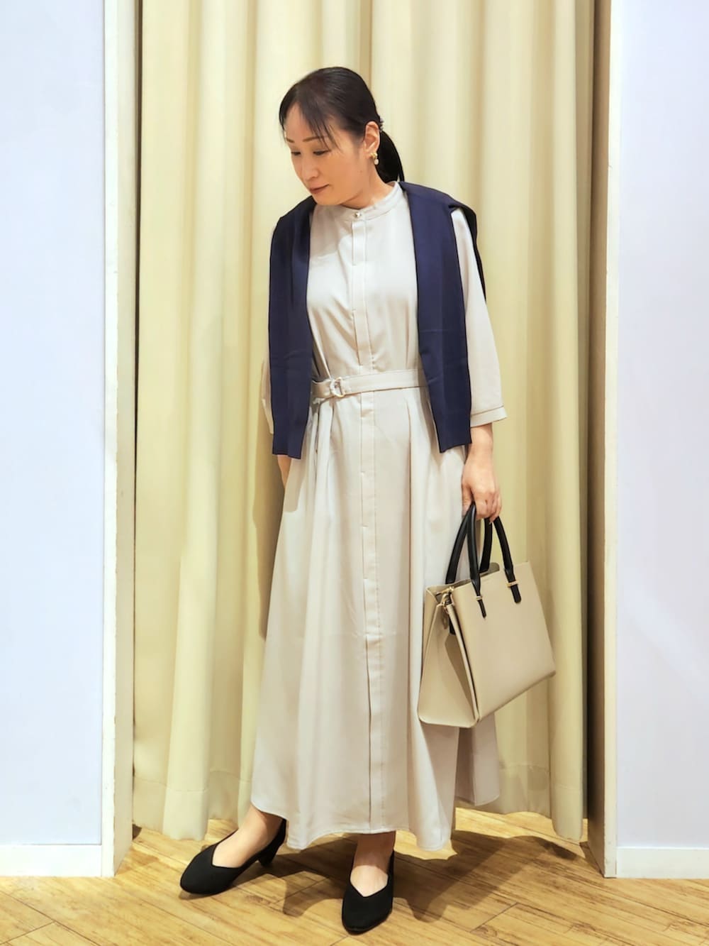 ブラック系のパンプス、ベージュ系のトートバッグ、ベージュ系のワンピースを着用したレディースの春コーディネートの5枚目の写真