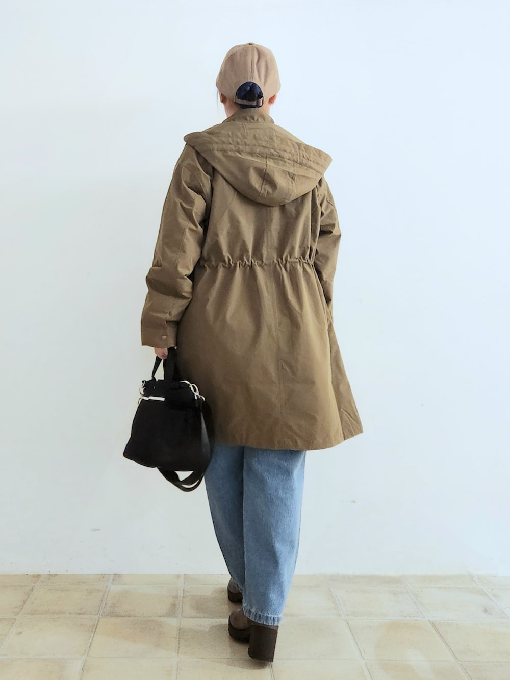 ブルー系のデニムパンツ、ブラウン系のブーツ、ブラック系のトートバッグを着用したレディースの秋コーディネートの4枚目の写真