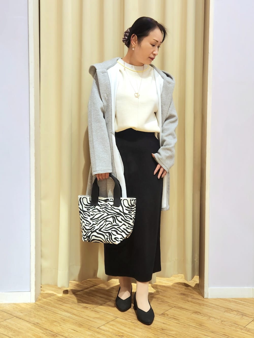 ブラック系のスカート、ブラック系のトートバッグ、ブラック系のパンプスを着用したレディースの冬コーディネートの2枚目の写真