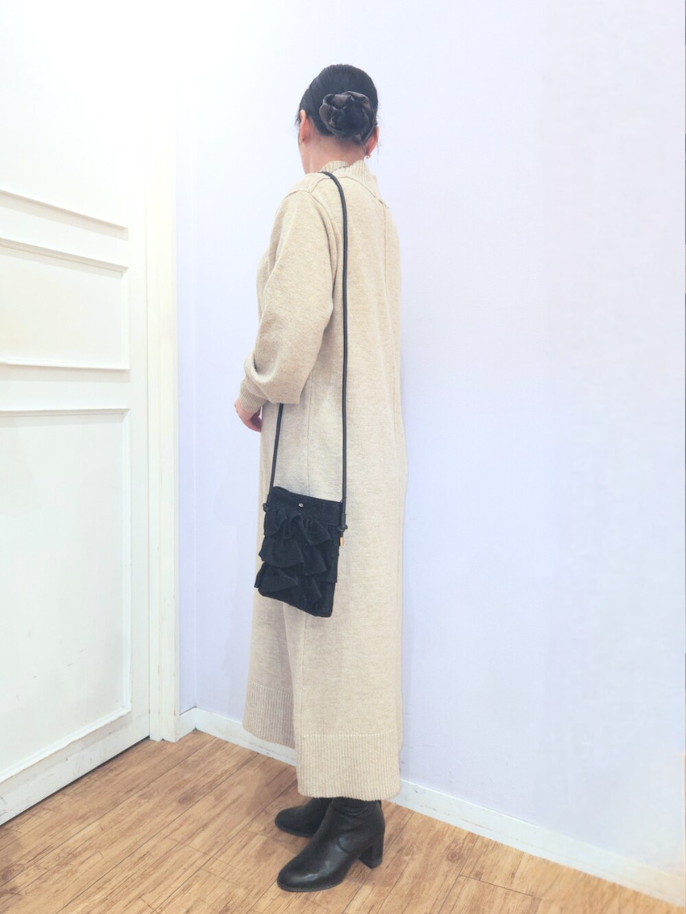 ブラック系のブーツ、ブラック系のショルダーバッグ、ベージュ系のワンピースを着用したレディースの冬コーディネートの2枚目の写真