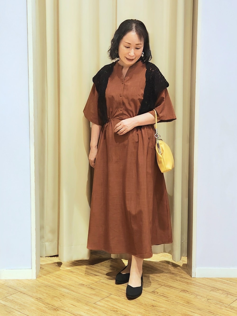 イエロー系のショルダーバッグ、ブラック系のパンプス、オレンジ系のワンピースを着用したレディースの夏コーディネートの2枚目の写真