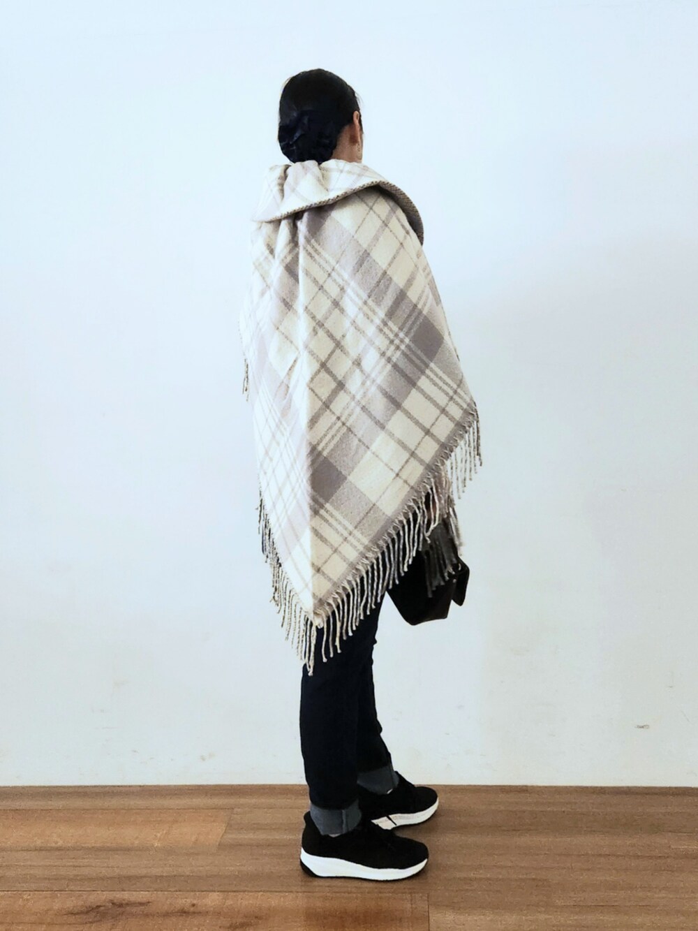 ブラック系のスニーカー、グリーン系のチュニック、ブルー系のデニムパンツを着用したレディースの秋コーディネートの3枚目の写真