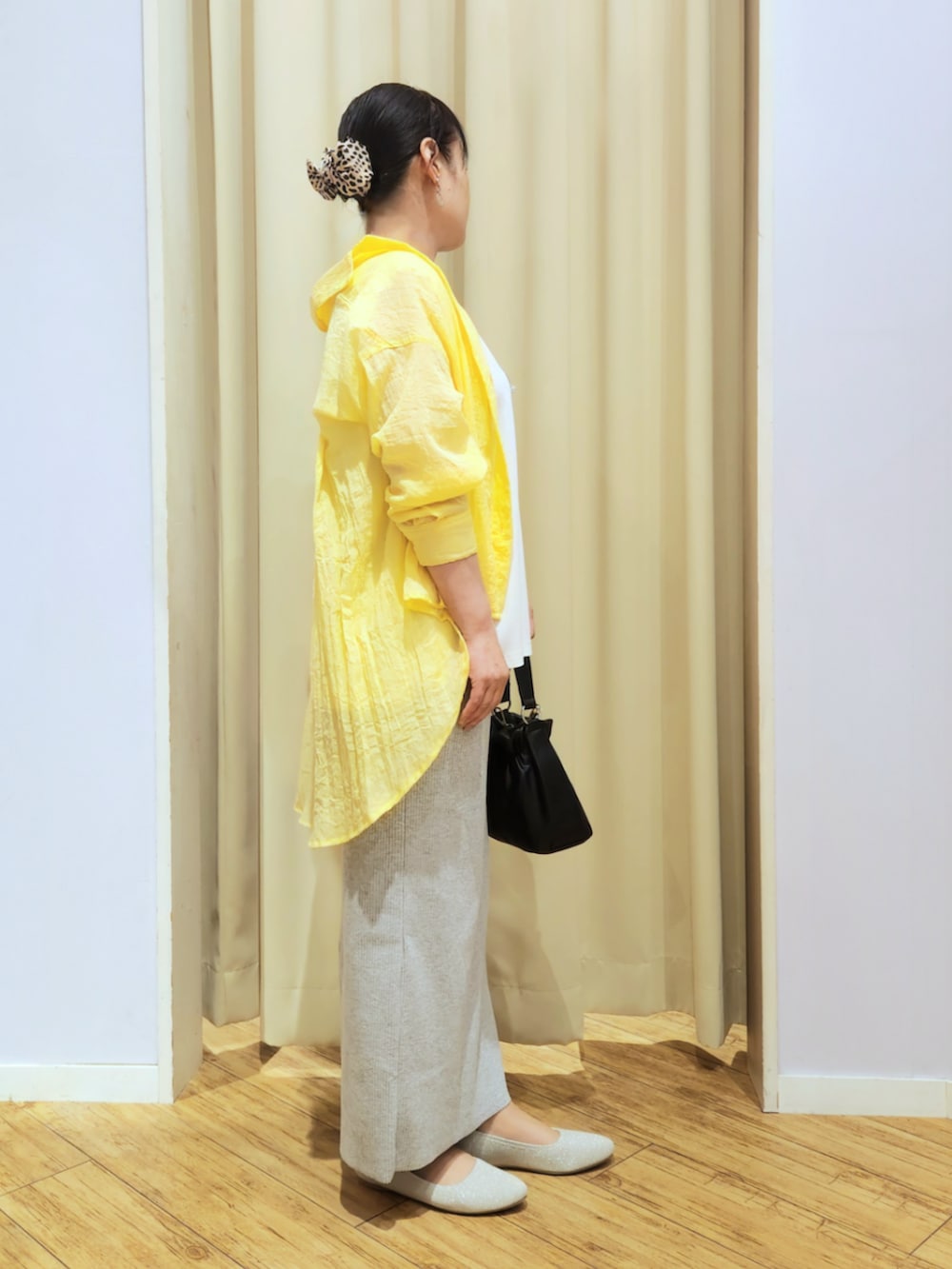 ベージュ系のパンプス、グレー系のスカート、ブラック系のショルダーバッグを着用したレディースの春コーディネートの2枚目の写真