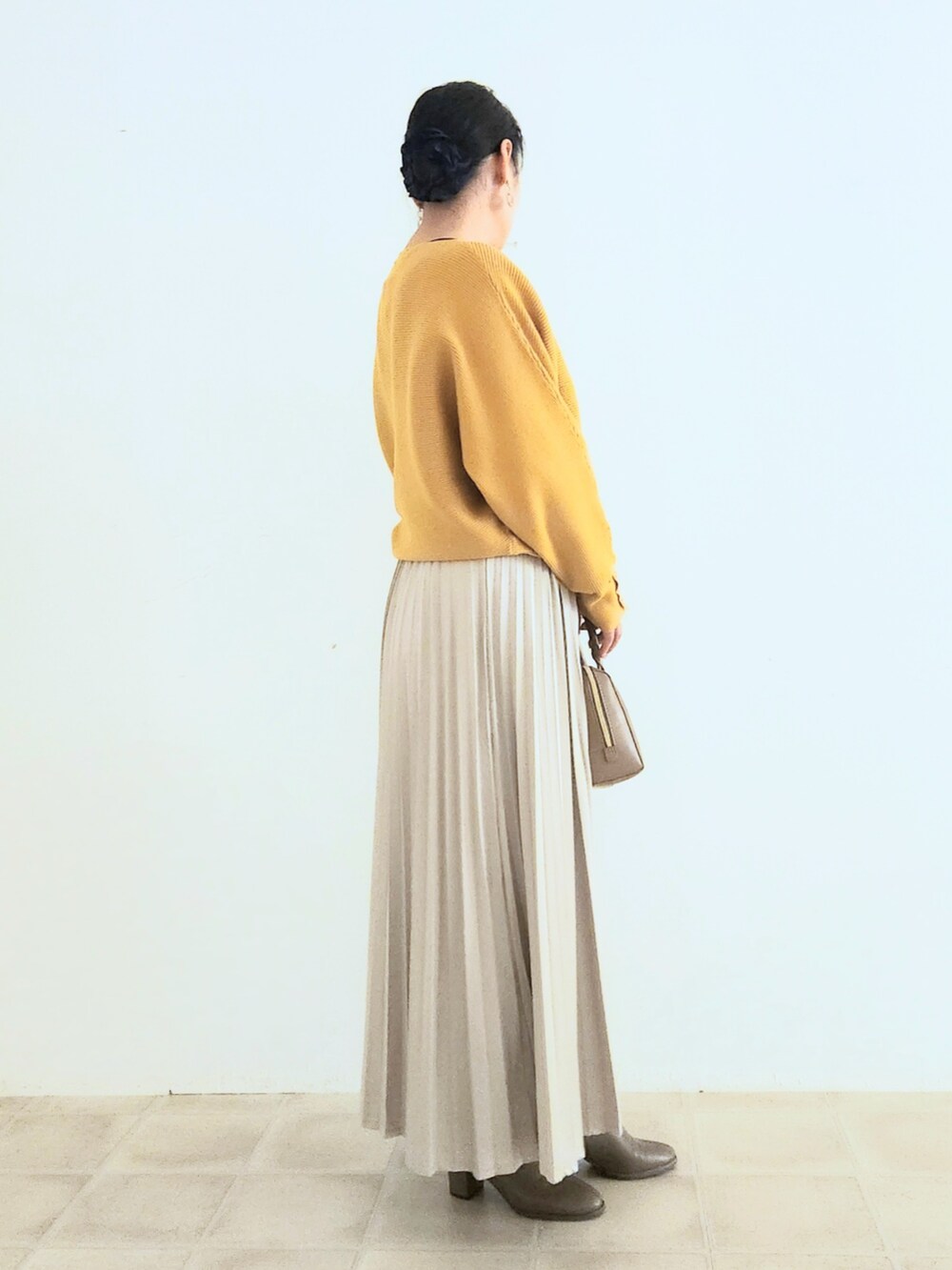 ベージュ系のスカート、ブラウン系のブーツ、イエロー系のニット/セーターを着用したレディースの秋コーディネートの3枚目の写真