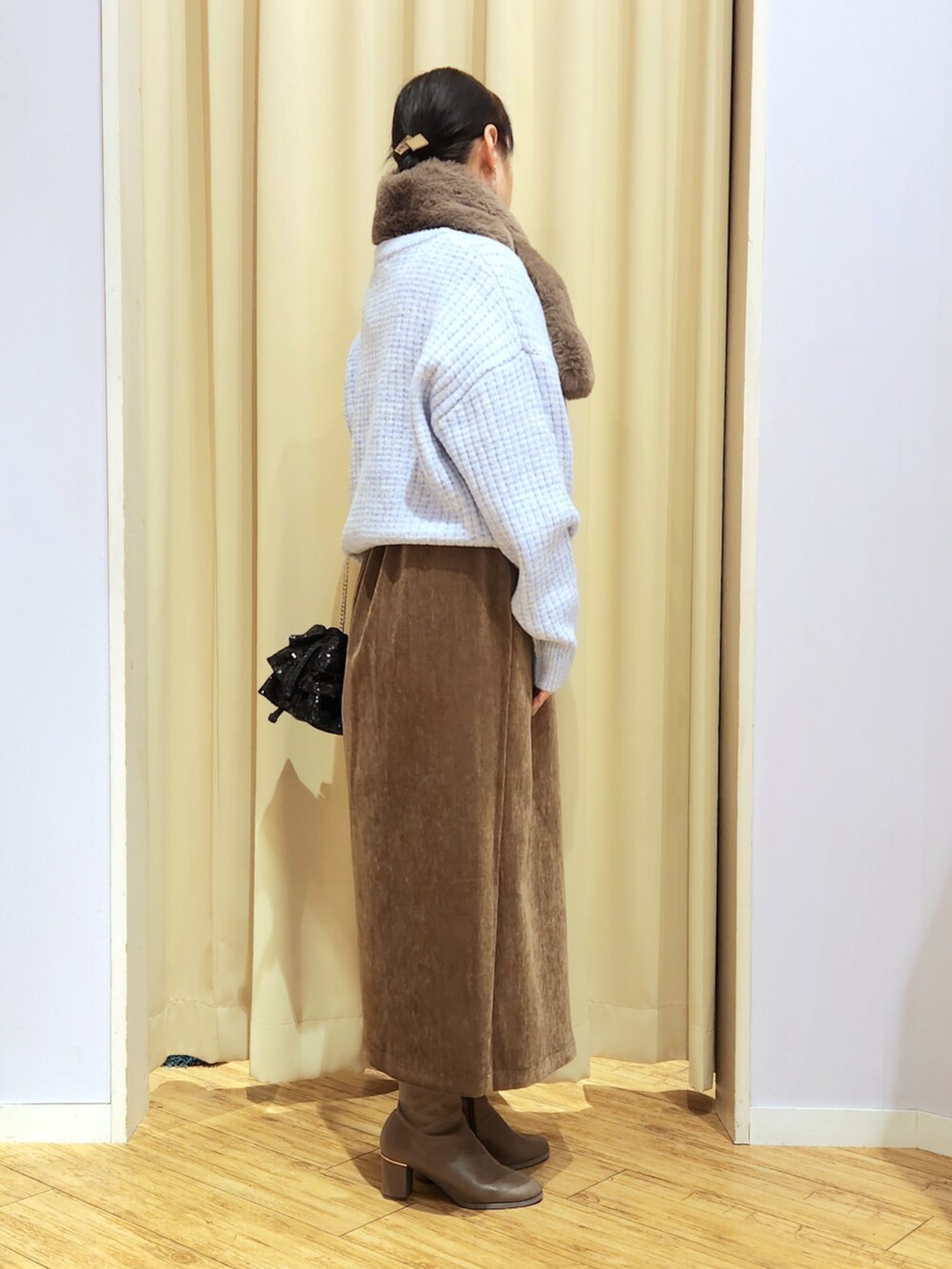 ブラウン系のブーツ、ブラウン系のスカート、ブラック系のショルダーバッグを着用したレディースの冬コーディネートの2枚目の写真