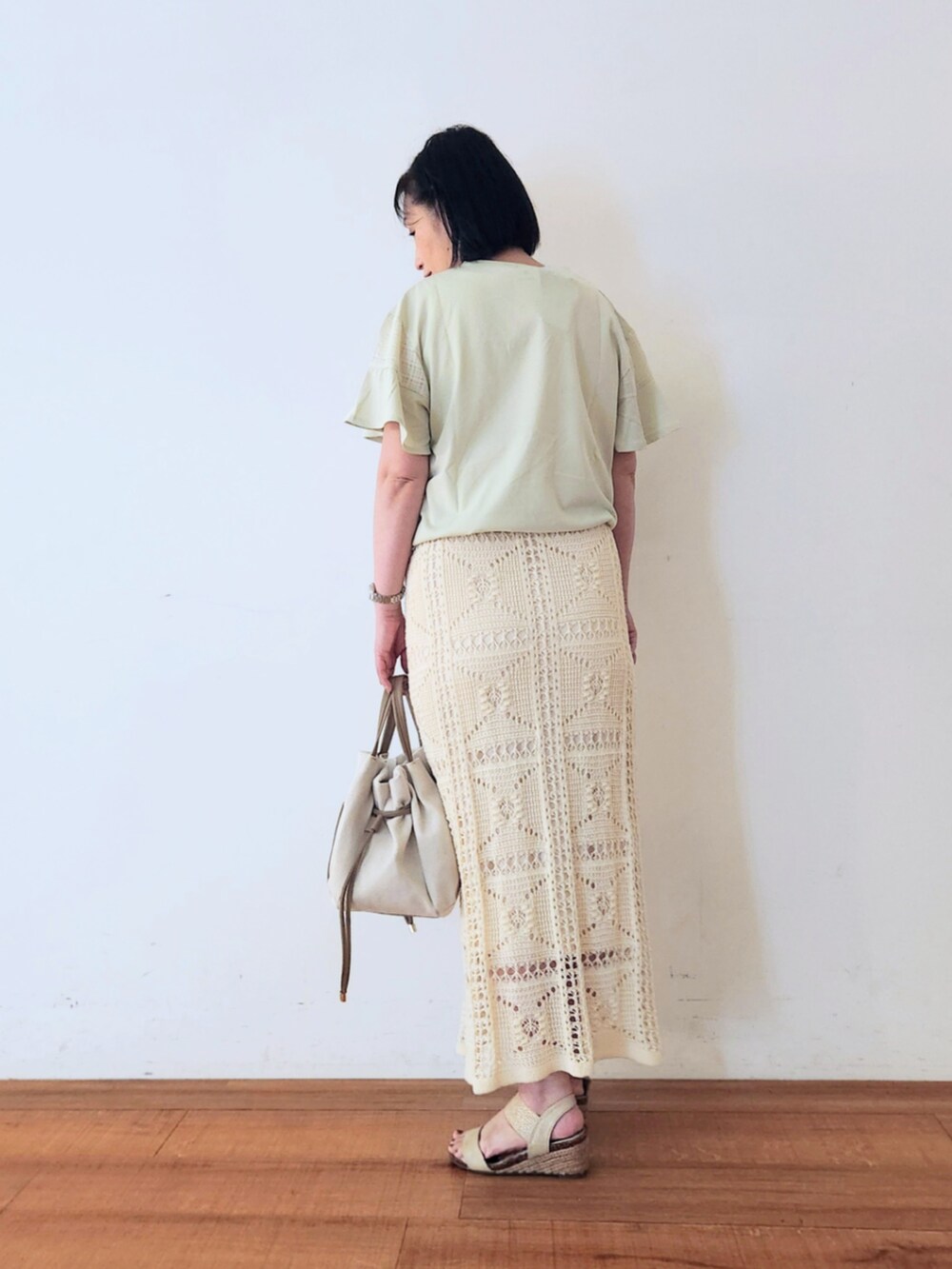 ホワイト系のスカート、ゴールド系のサンダル、ベージュ系のトートバッグを着用したレディースの夏コーディネートの3枚目の写真