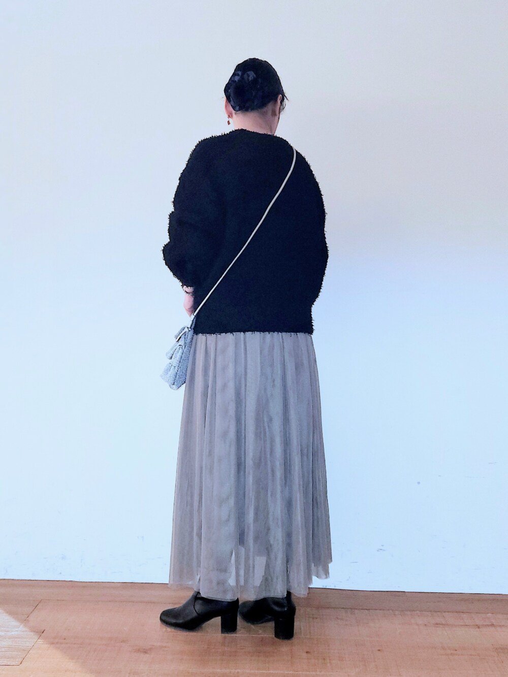 ブラック系のブーツ、シルバー系のショルダーバッグ、ブラウン系のスカートを着用したレディースの冬コーディネートの3枚目の写真