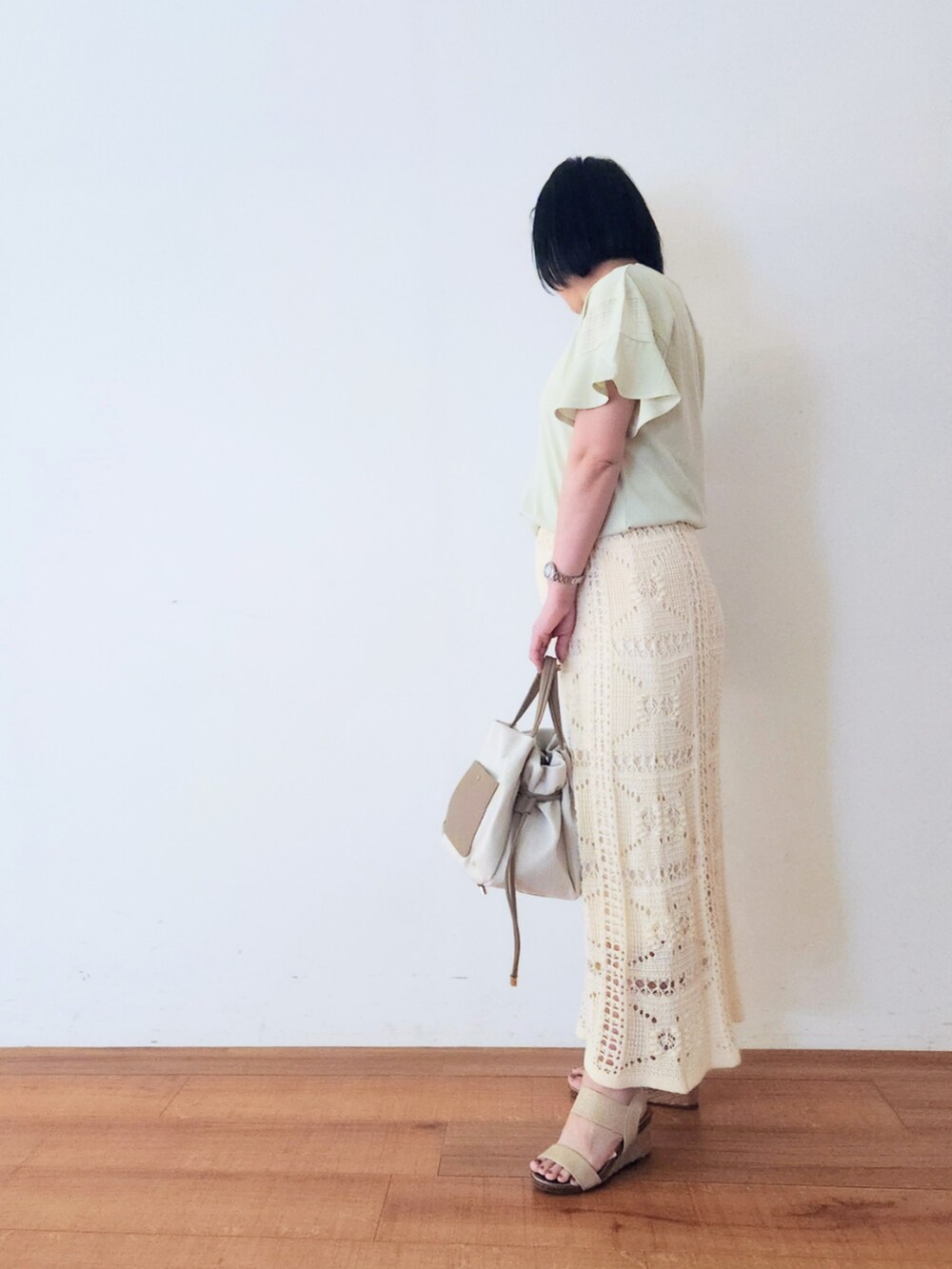 ホワイト系のスカート、ゴールド系のサンダル、ベージュ系のトートバッグを着用したレディースの夏コーディネートの2枚目の写真
