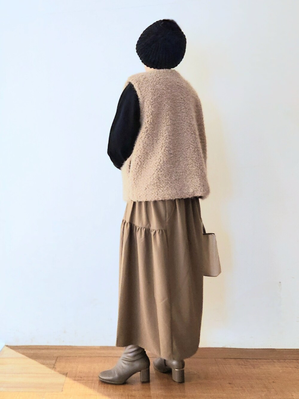 ベージュ系のトートバッグ、ブラウン系のブーツ、ブラック系のワンピースを着用したレディースの秋コーディネートの3枚目の写真