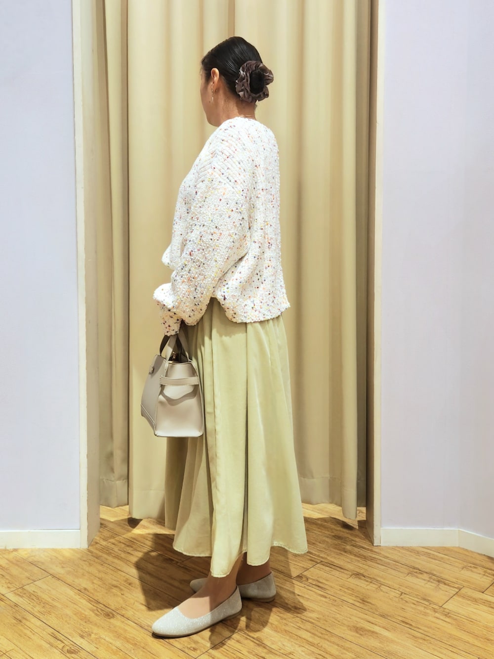 ホワイト系のカーディガン/ボレロ、ベージュ系のパンプス、グリーン系のスカートを着用したレディースの冬コーディネートの2枚目の写真