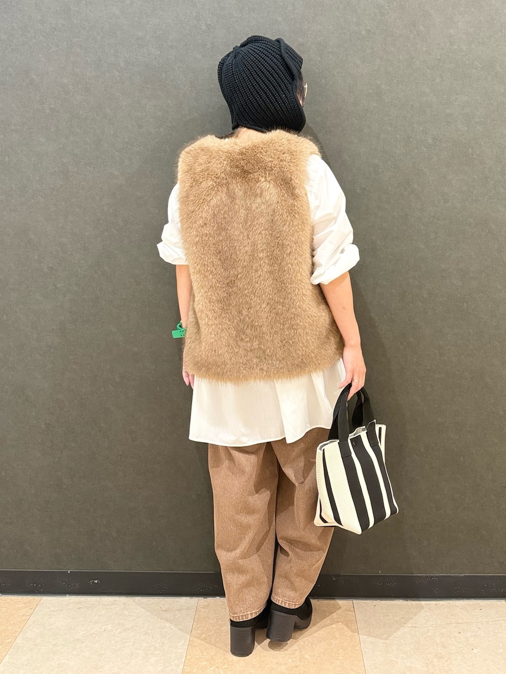 イエロー系のベスト、ホワイト系のチュニック、ブラウン系のデニムパンツを着用したレディースの秋コーディネートの4枚目の写真