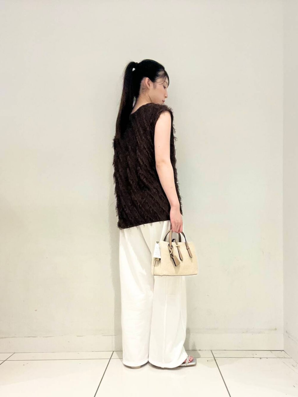 ホワイト系のハンドバッグ、ホワイト系のキャミソール、シルバー系のサンダルを着用したレディースの夏コーディネートの2枚目の写真