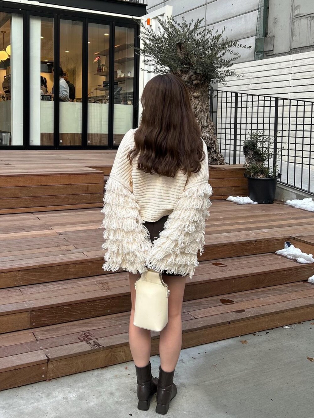 ブラウン系のブーツ、ブラウン系のスカート、ベージュ系のショルダーバッグを着用したレディースの冬コーディネートの3枚目の写真