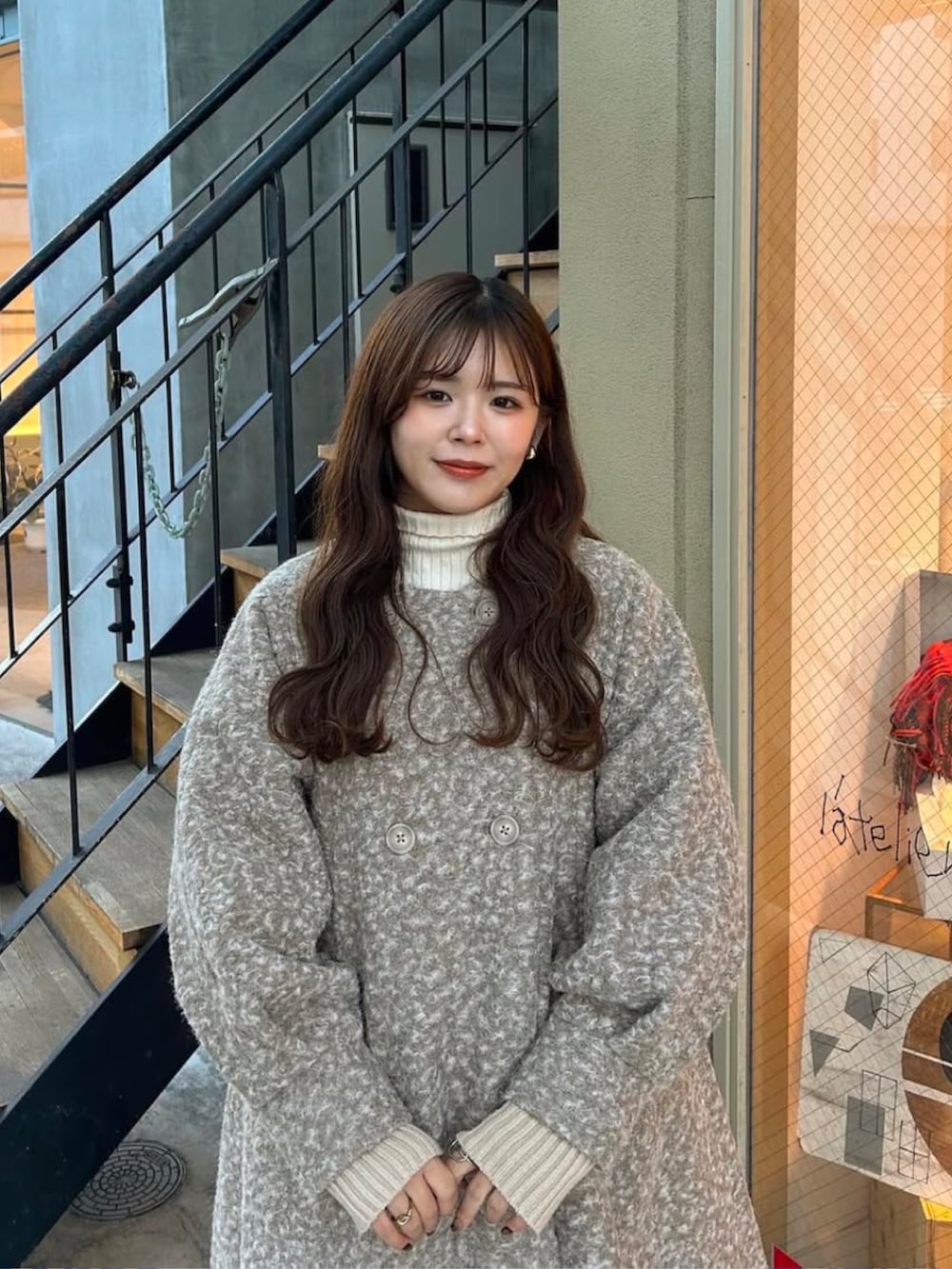 ベージュ系のノーカラーコート、ブラウン系のバッグ、その他のシューズを着用したレディースの冬コーディネートの2枚目の写真