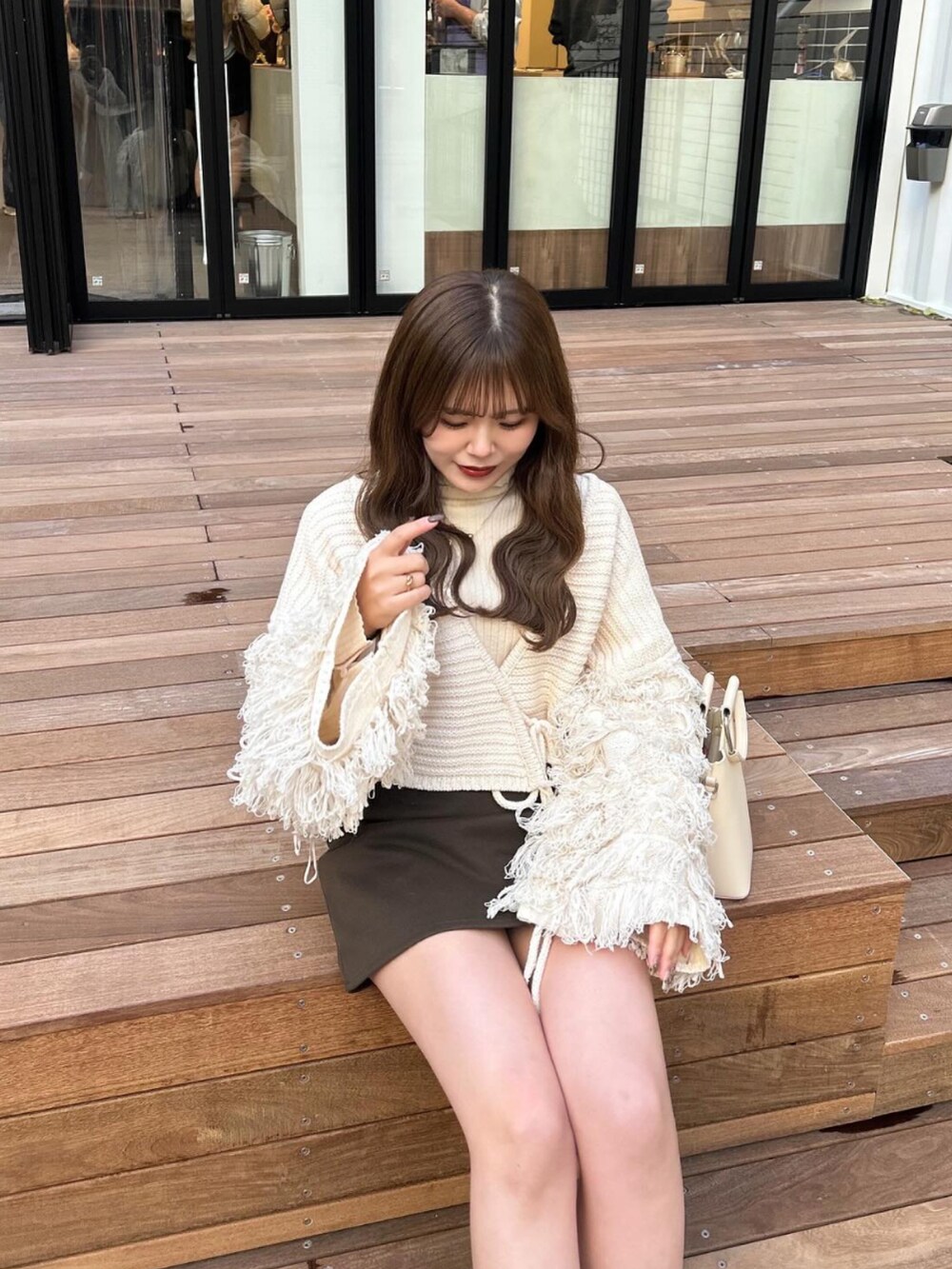 ブラウン系のブーツ、ブラウン系のスカート、ベージュ系のショルダーバッグを着用したレディースの冬コーディネートの2枚目の写真