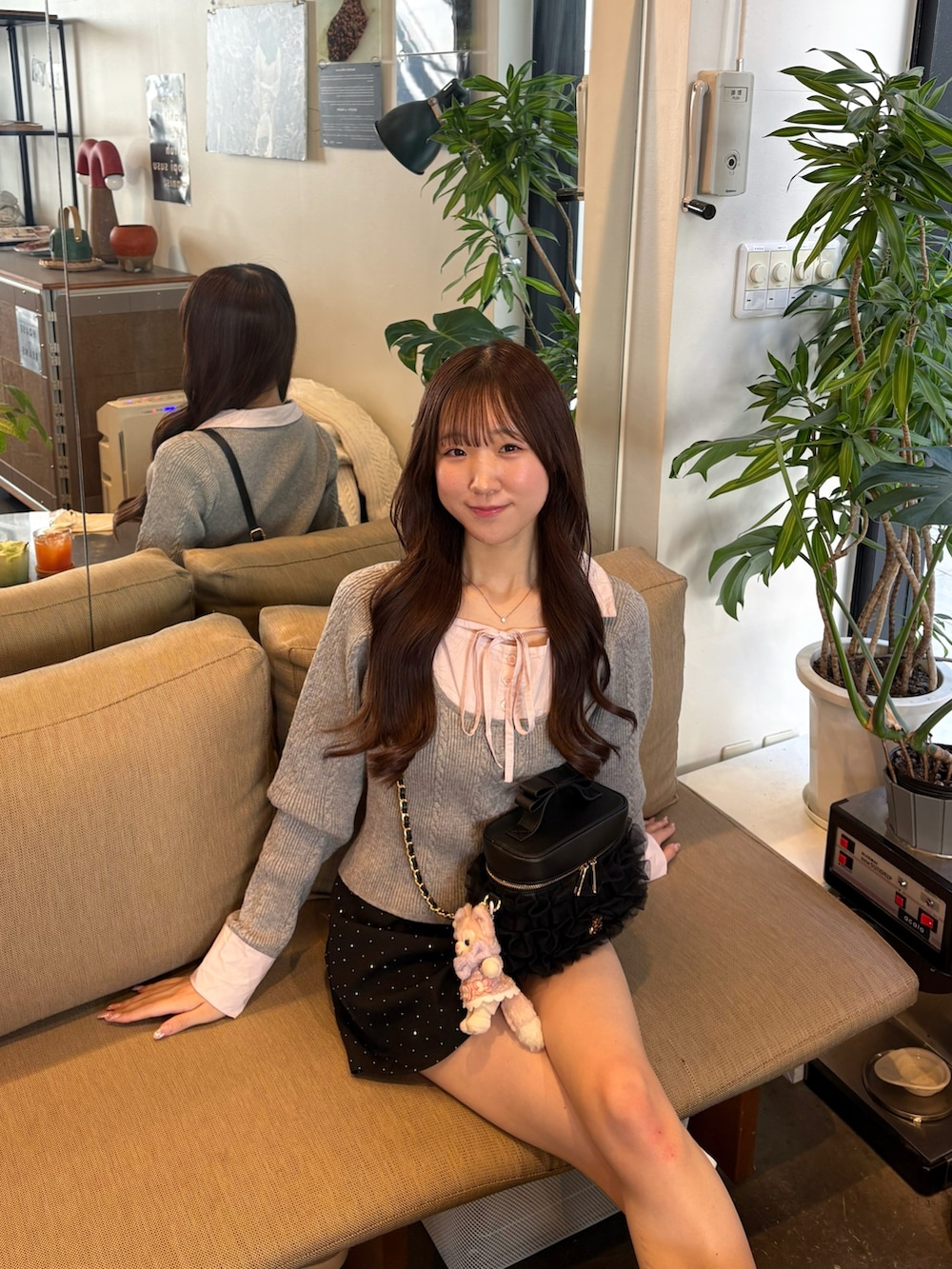 グレー系のニット/セーター、グレー系のスニーカー、ブラック系のショルダーバッグを着用したレディースの冬コーディネートの2枚目の写真